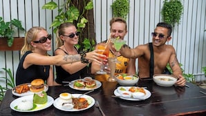 A group of people toasting with drinks at a table with various dishes. - Mad Monkey Kampot (Kampot)
