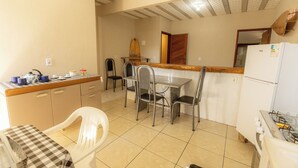 A compact kitchen with a dining table, chairs, a refrigerator, and a gas stove. - Apto c Varanda Garagem e Vista das Montanhas (Angra dos Reis)
