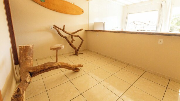 A room with a tiled floor, a wooden branch structure, and a surfboard on the wall. - Apto c Varanda Garagem e Vista das Montanhas (Angra dos Reis)