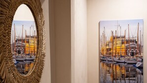 A framed painting of a marina with boats and buildings reflected in calm water. - Sette Vele Rooms  (Trieste)
