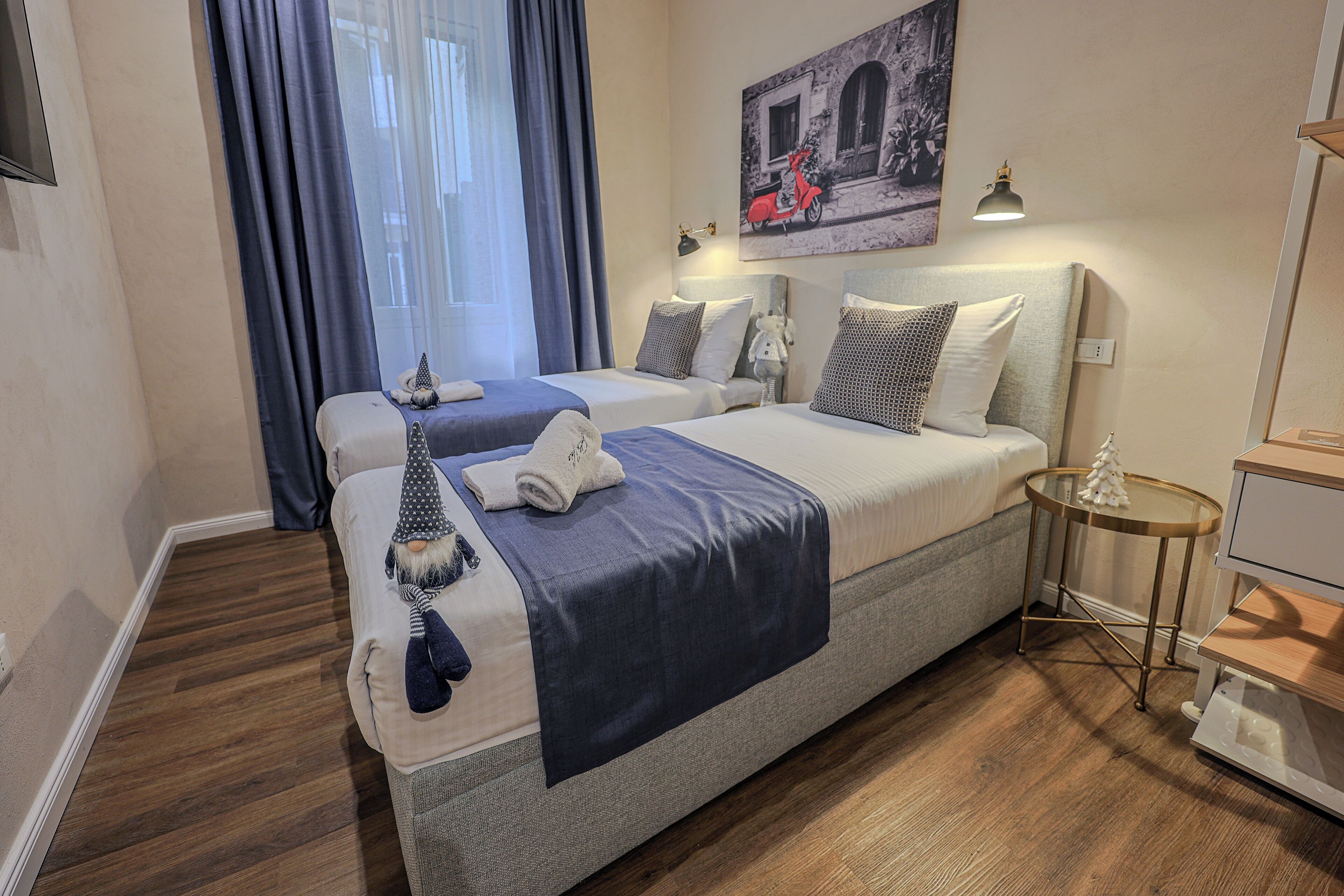Ein Hotelzimmer mit zwei Betten, einem kleinen Tisch, einer Lampe und einem Bild an der Wand.