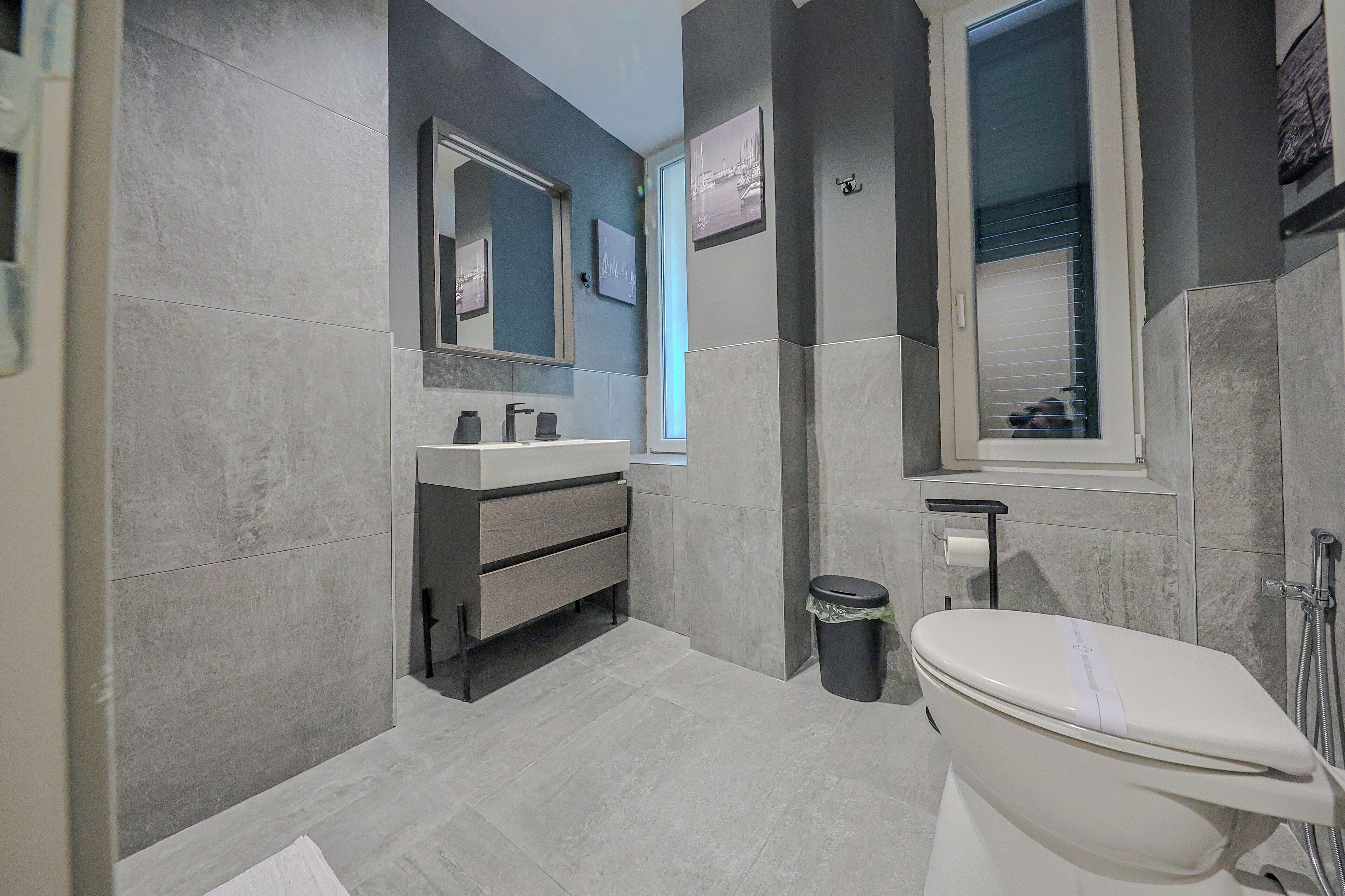 A modern bathroom with a toilet, sink, and mirror.
