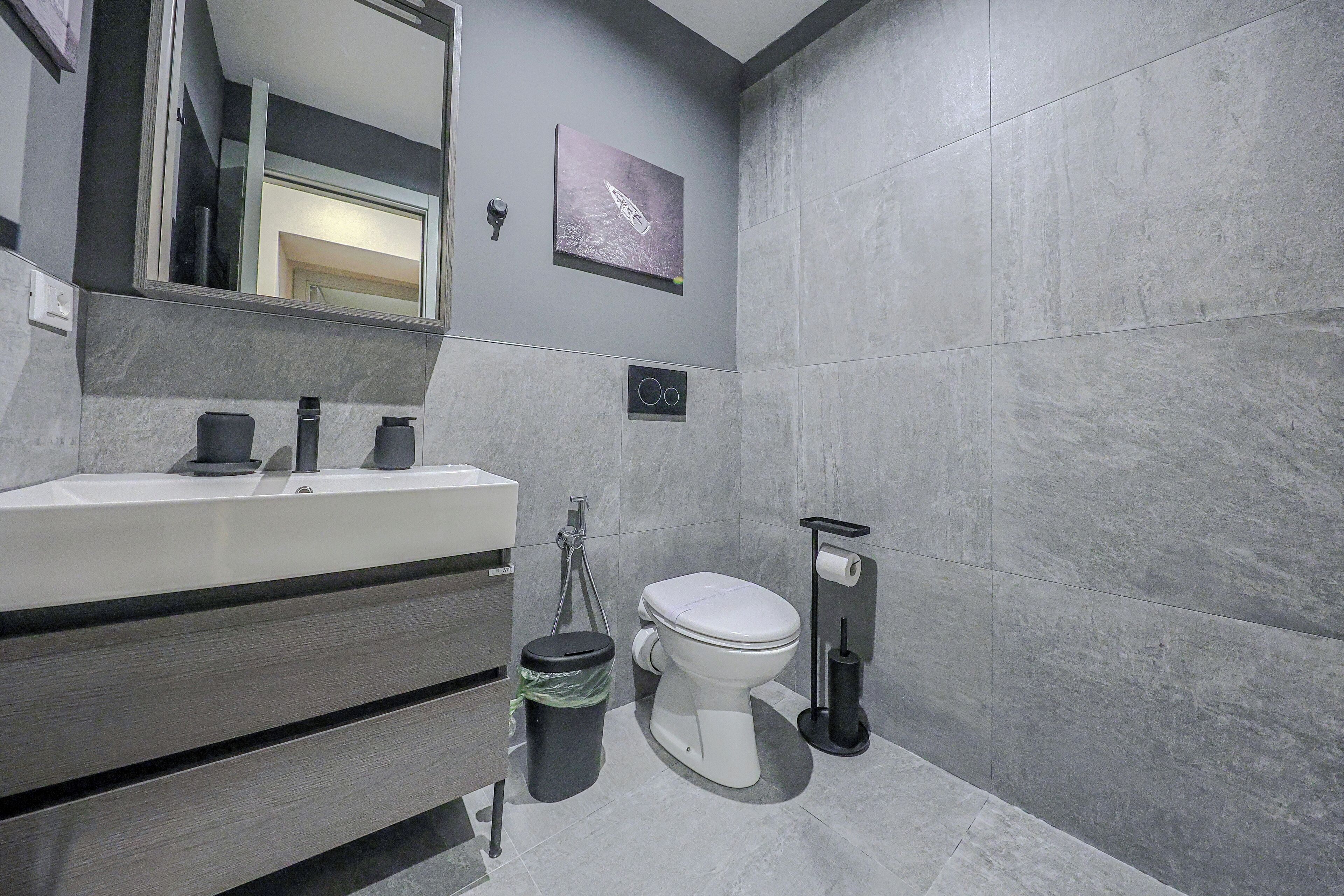 Ein modernes Badezimmer mit Waschbecken, Spiegel und Toilette in Weiß.
