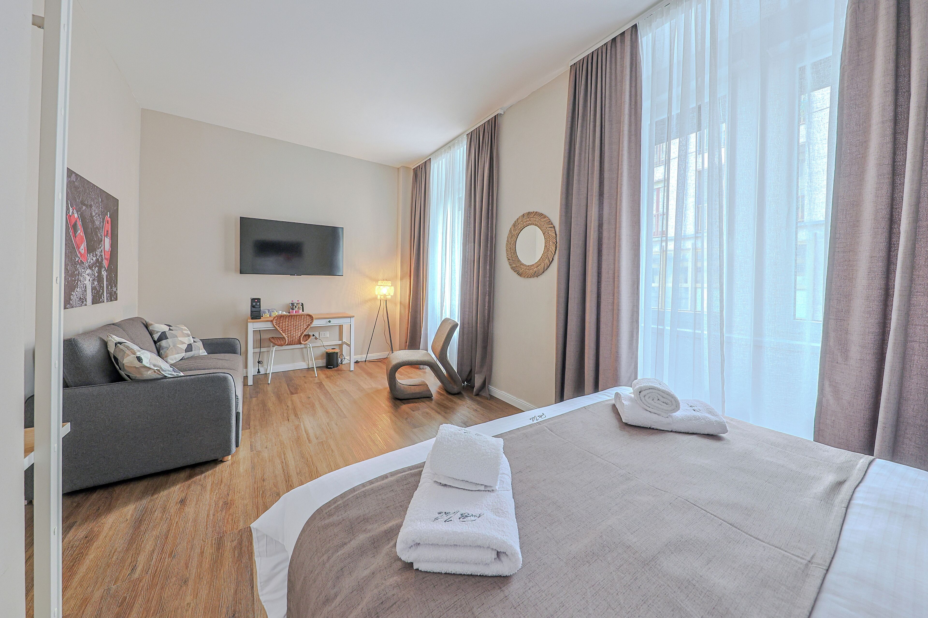 A hotel room with a bed, a sofa, a desk, and a TV.