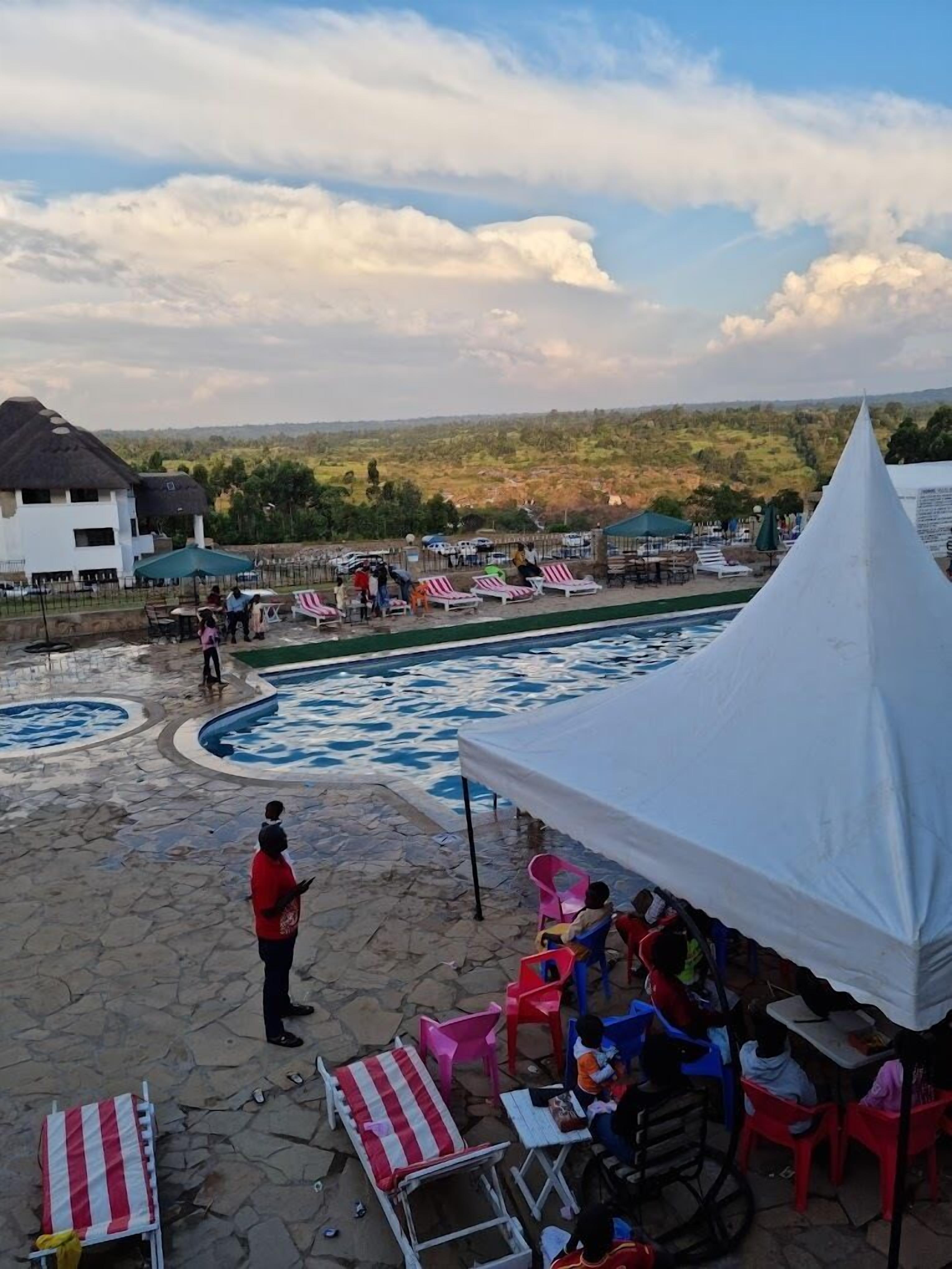 Un área de piscina con sillones de descanso y una carpa, rodeada por un patio de piedra y vistas a un paisaje montañoso.