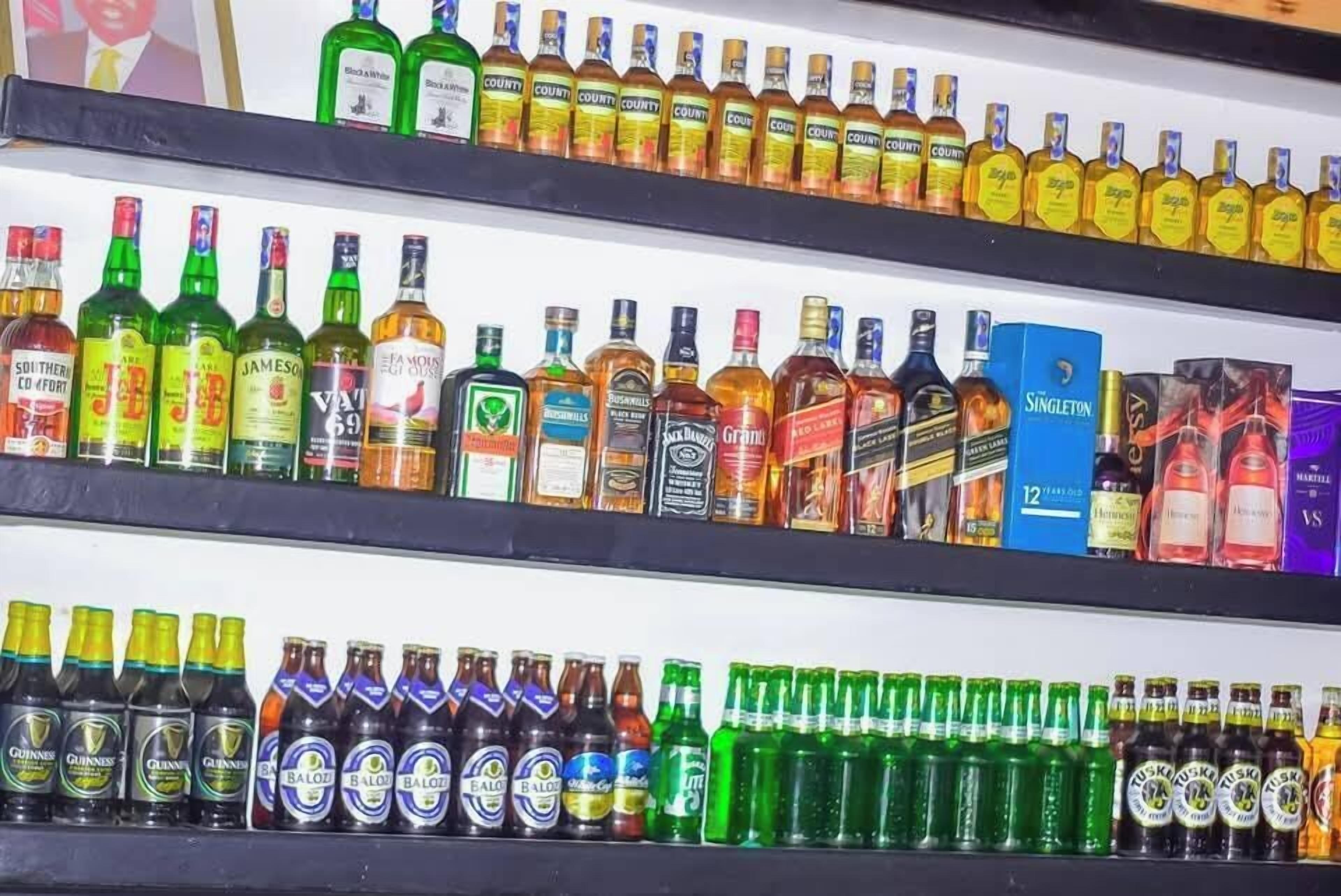 A shelf with various liquor bottles, including brands like Jameson, Bacardi, and Guinness.