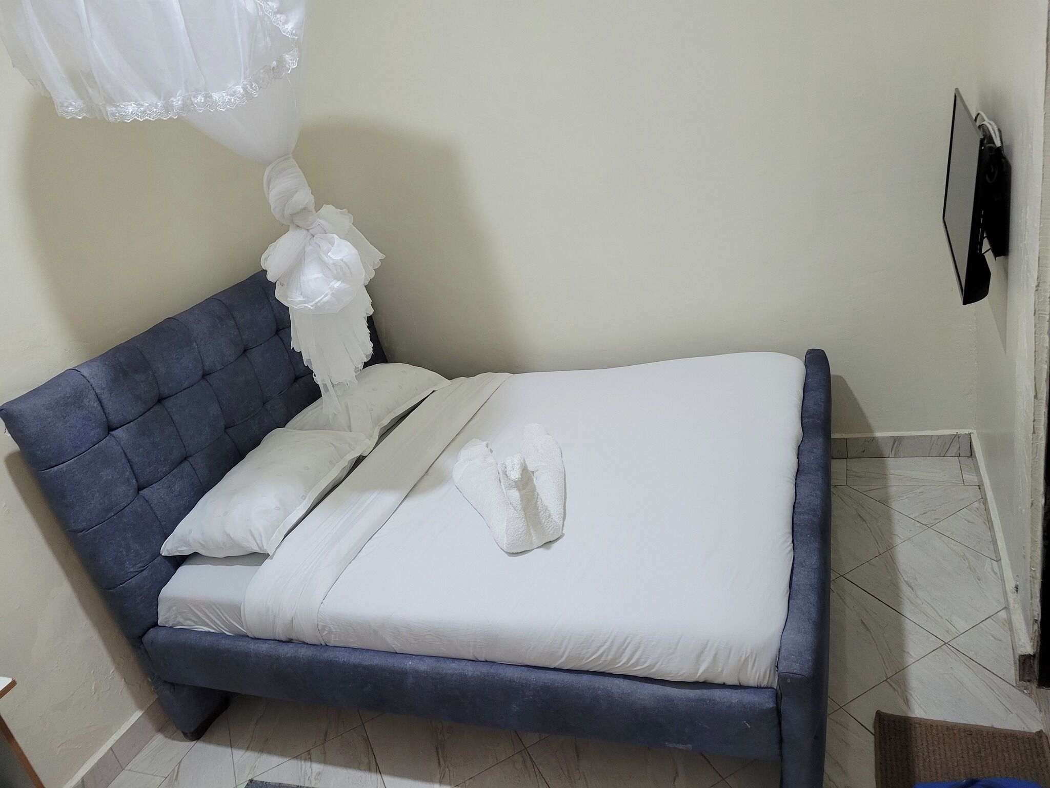 A bed with a tufted headboard, white bedding, and a decorative white canopy.
