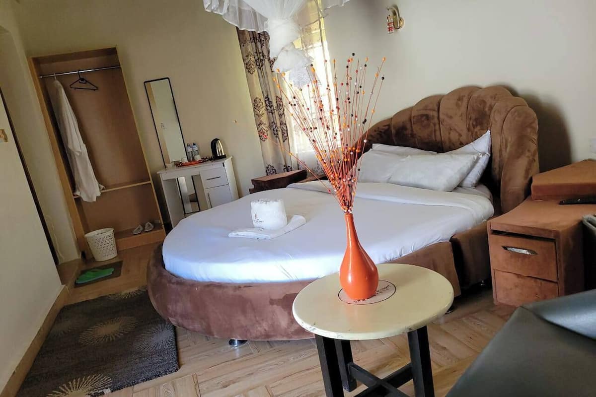 Un dormitorio con cama, mesita de noche y una pequeña mesa con un florero.