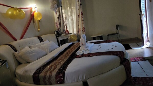 A hotel room with two beds, a desk, and a chair. There are balloons on the wall and a window with curtains. - Falls View Resort Nabuyole (Webuye)