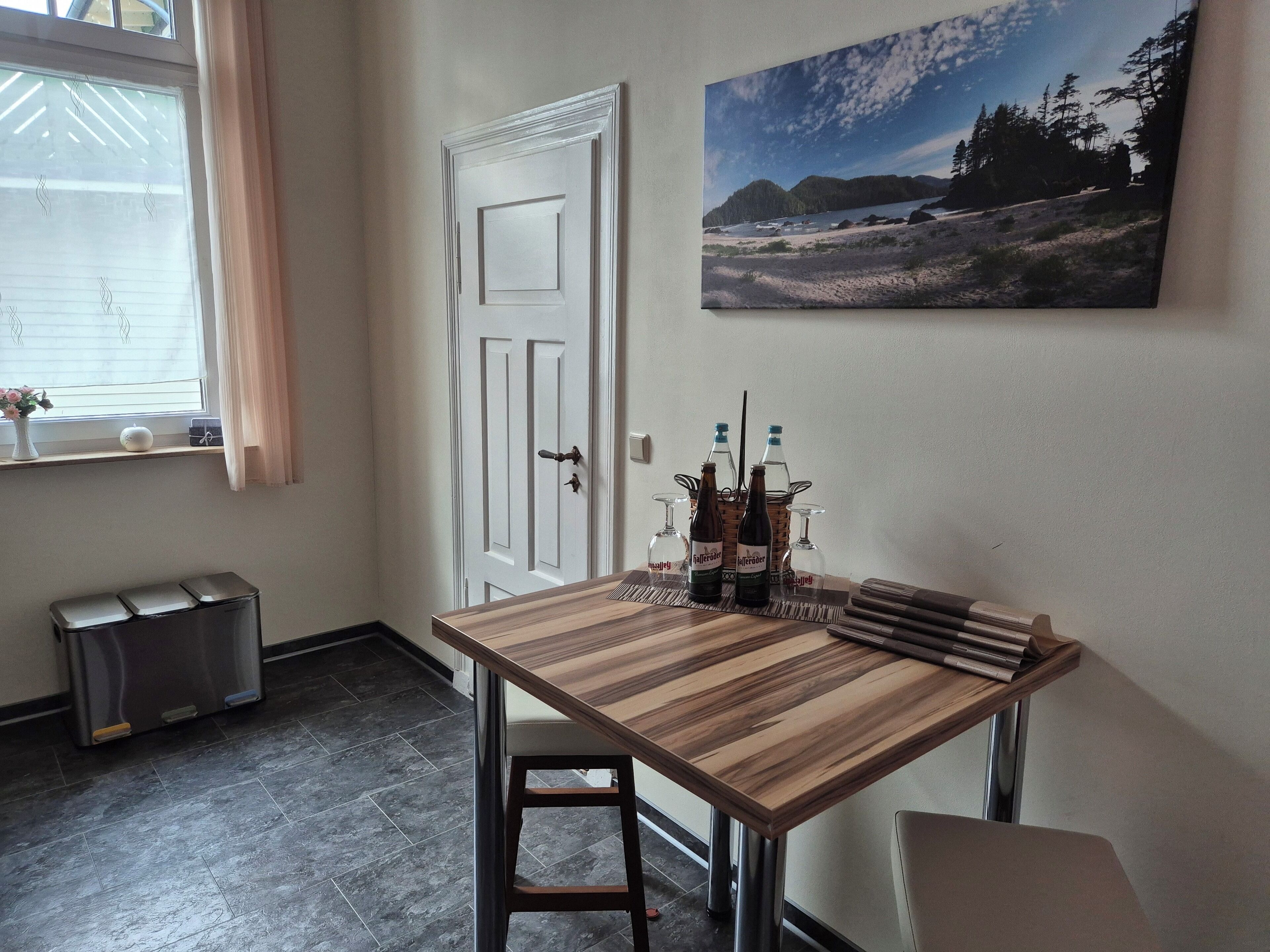 A dining area with a wooden table, chairs, and a painting on the wall.