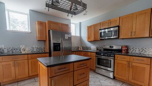 A modern kitchen with wooden cabinets, stainless steel appliances, and a tiled backsplash. - Spacious Modern 7BR Retreat ~ 3 Story Gem in Pittsburgh (Pittsburgh)