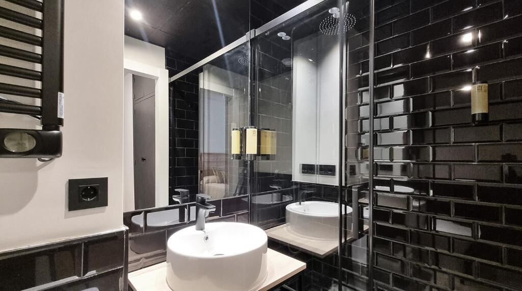 Un baño moderno con un espejo grande, dos lavamanos y una ducha con paredes de vidrio.