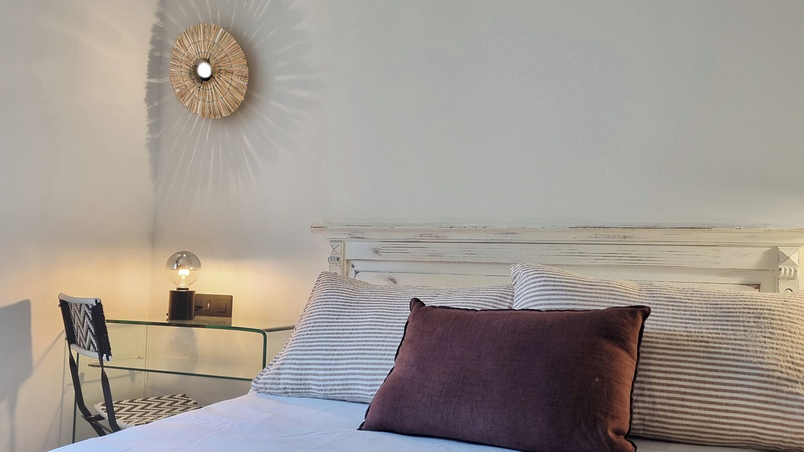 Une chambre à coucher avec un lit, une table de chevet avec une lampe et un luminaire fixé au mur.