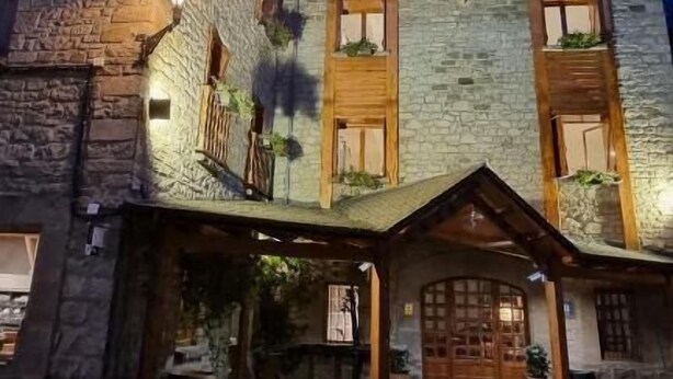 A stone building with a wooden balcony and a covered entrance. - La Posada de Ruba (Biescas)