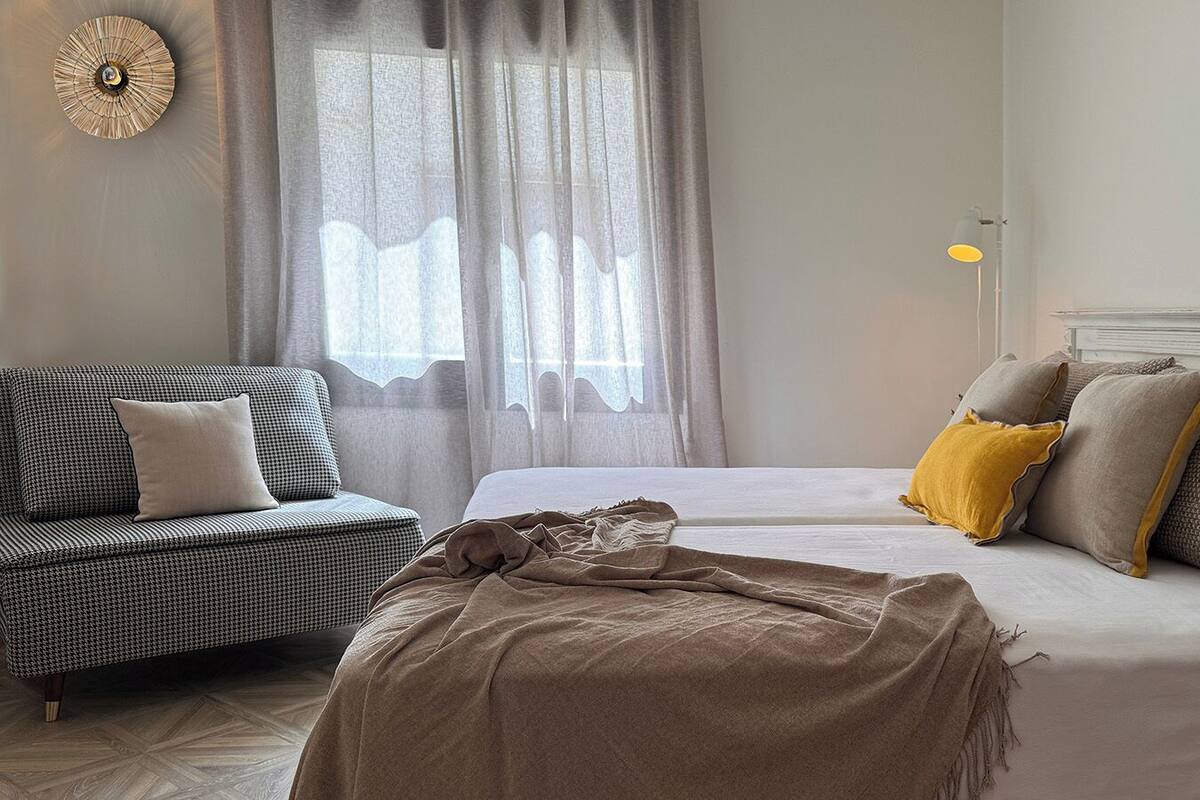 A bedroom with a bed, a sofa, and a lamp.