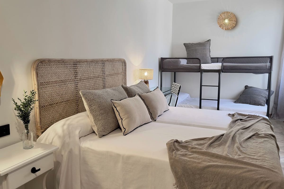 A bedroom with a bunk bed, a bedside table with a lamp, and a wall-mounted light fixture.