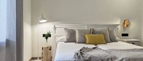 A neatly arranged bedroom with a bed, bedside tables, a lamp, and a wall-mounted light fixture.
