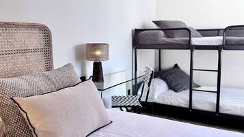 A bunk bed with a metal frame and a single bed with a woven headboard.