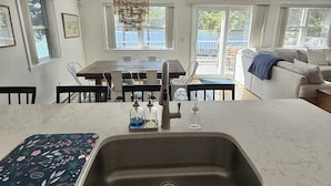 A modern kitchen with a large island, a dining area with a view, and a cozy seating area. - WATERFRONT ON THOMPSON LAKE (Oxford)