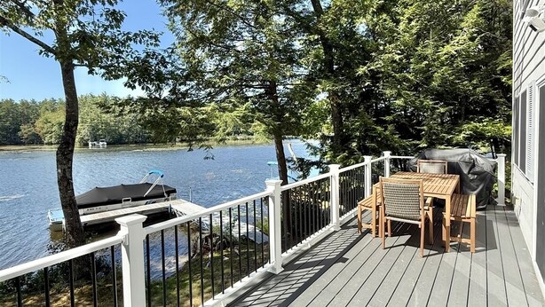 A wooden deck with a white railing overlooking a lake, a grill, and a table with chairs. - WATERFRONT ON THOMPSON LAKE (Oxford)