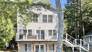 A two-story house with a balcony, a small porch, and a staircase leading to a deck. - WATERFRONT ON THOMPSON LAKE (Oxford)