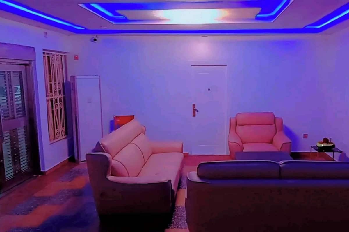 Ein Wohnzimmer mit zwei Sofas, einem Fernsehgerät an der Wand und einer Tür im Hintergrund.