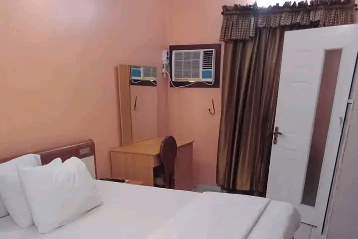 Ein Hotelzimmer mit Bett, Schreibtisch, Klimaanlage und einer Tür.