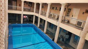 En pool med flera nivåer som erbjuder en tydlig utsikt över den omgivande arkitekturen, inklusive balkonger och kolonner.