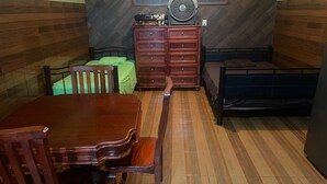 A room with a wooden dining table, chairs, a bed, a dresser, and a fan. - Estancia La Quinta María 1. (Veracruz)