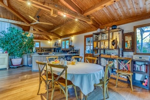 Un intérieur en bois comprenant une table à manger, des chaises, une plante en pot et un coin cuisine.