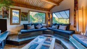 Ein modernes Interieur mit Holzboden, einem Ecksofa und großen Fenstern.
