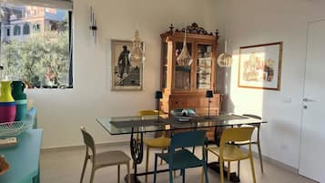 Un coin repas avec une table en verre, des chaises colorées et un buffet en bois.