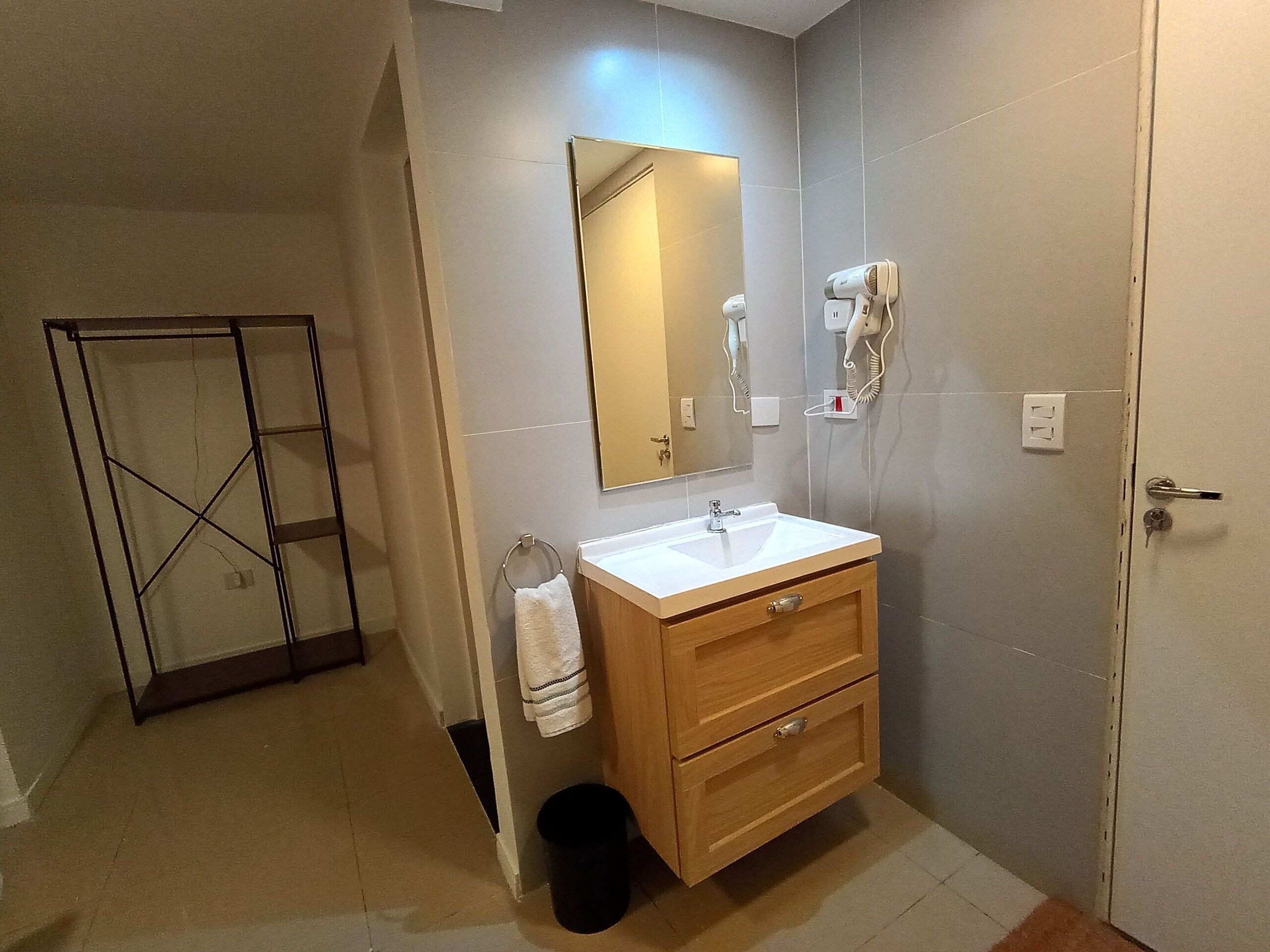 Une salle de bain avec un meuble-lavabo en bois, un évier, un miroir et deux sèche-cheveux fixés au mur.