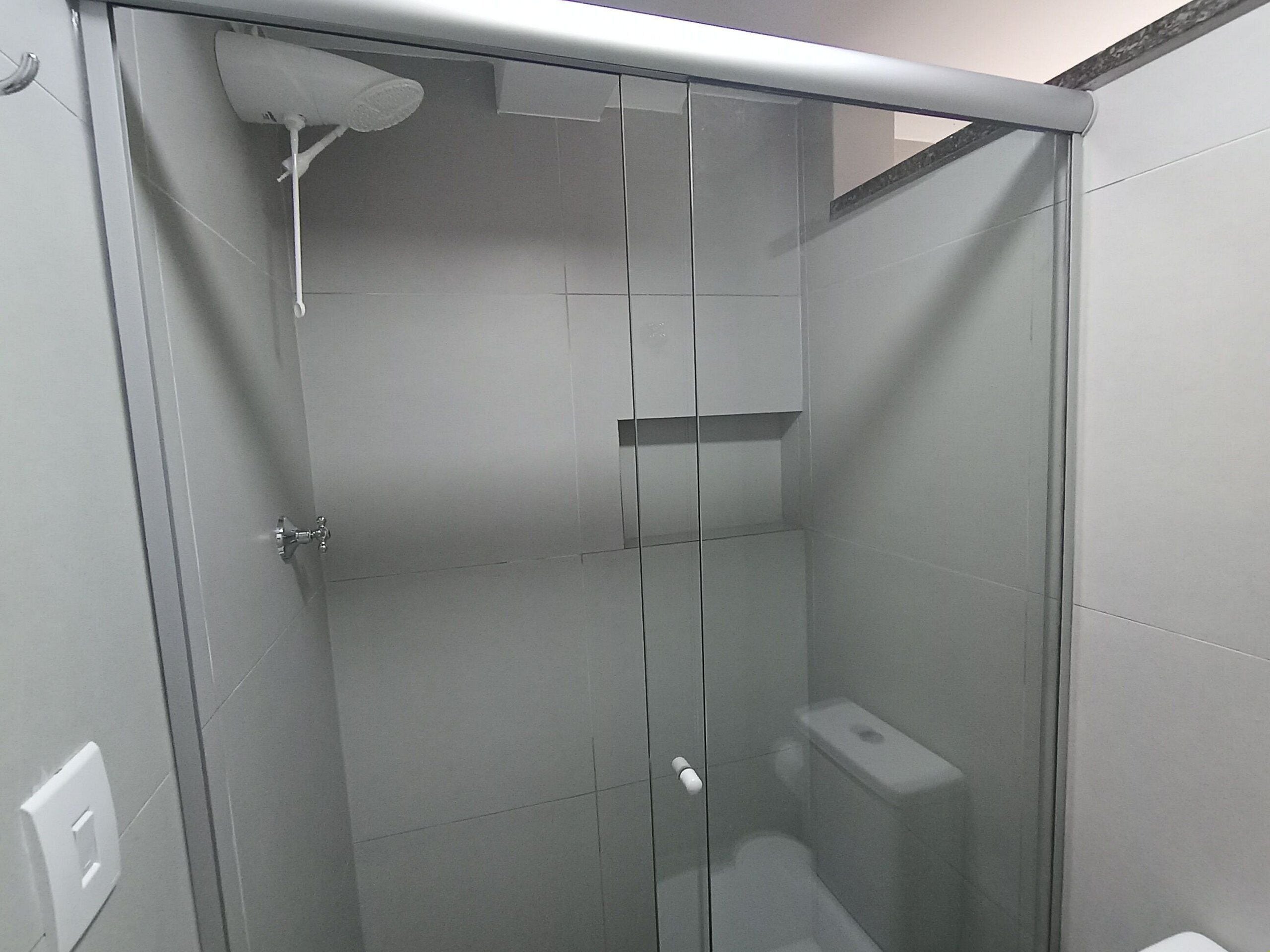 A glass-enclosed shower stall with a toilet and a towel rack.