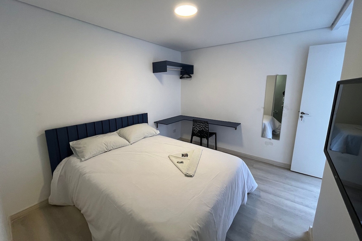 Ein Schlafzimmer mit Bett, Schreibtisch, Stuhl und Spiegel.