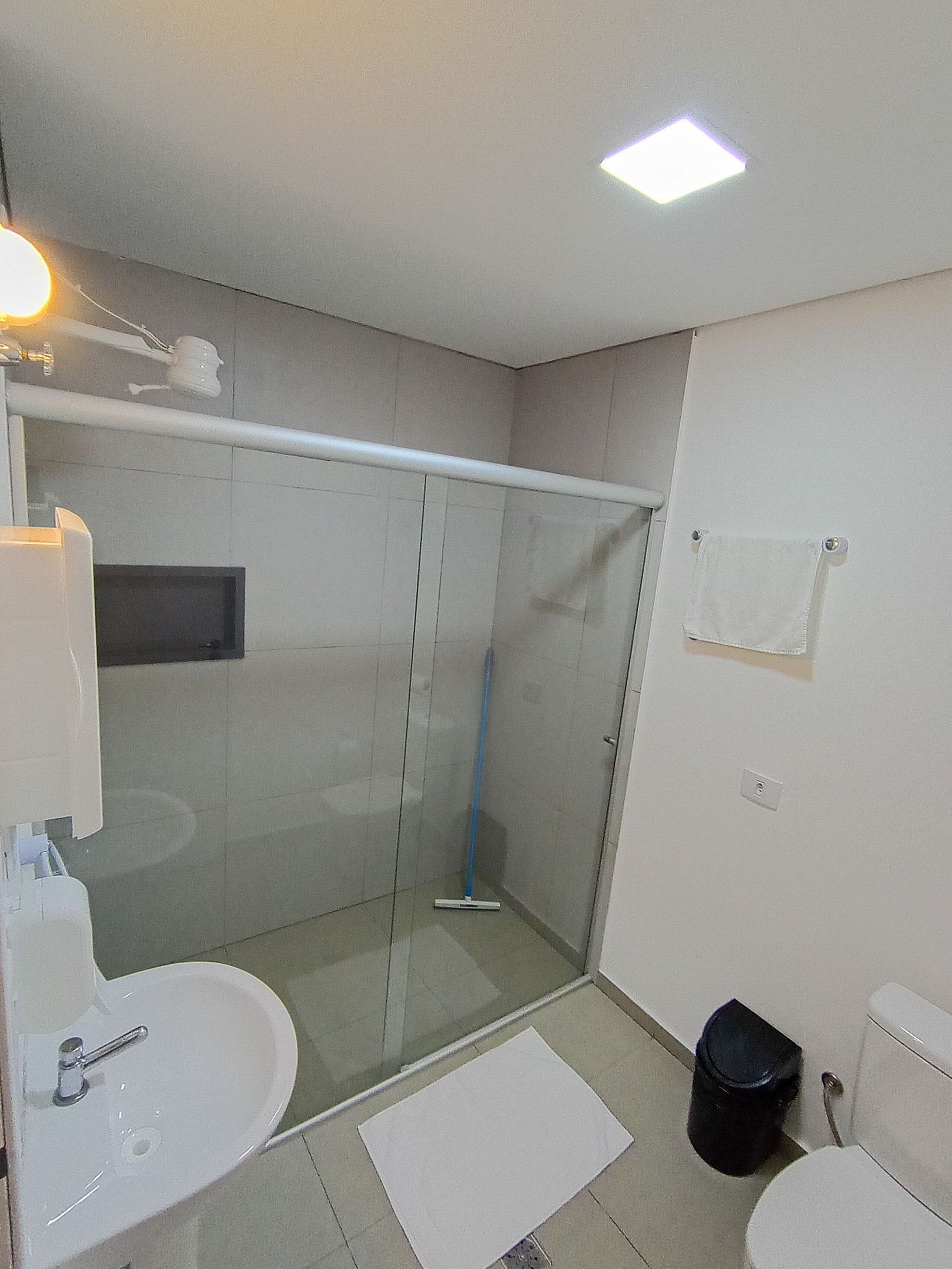 Un baño moderno con cabina de ducha de vidrio, un lavabo blanco y un inodoro.