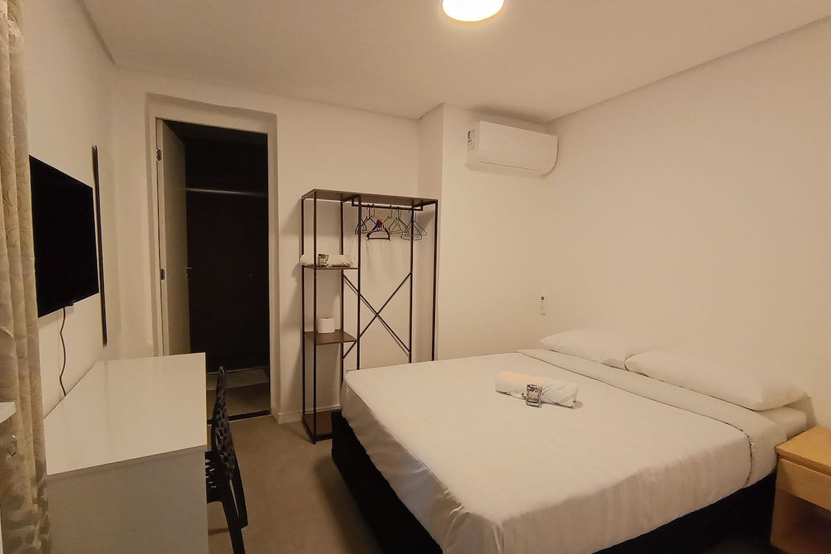 Ein Schlafzimmer mit Bett, Schreibtisch, Stuhl, Kleiderschrank und Fernseher.