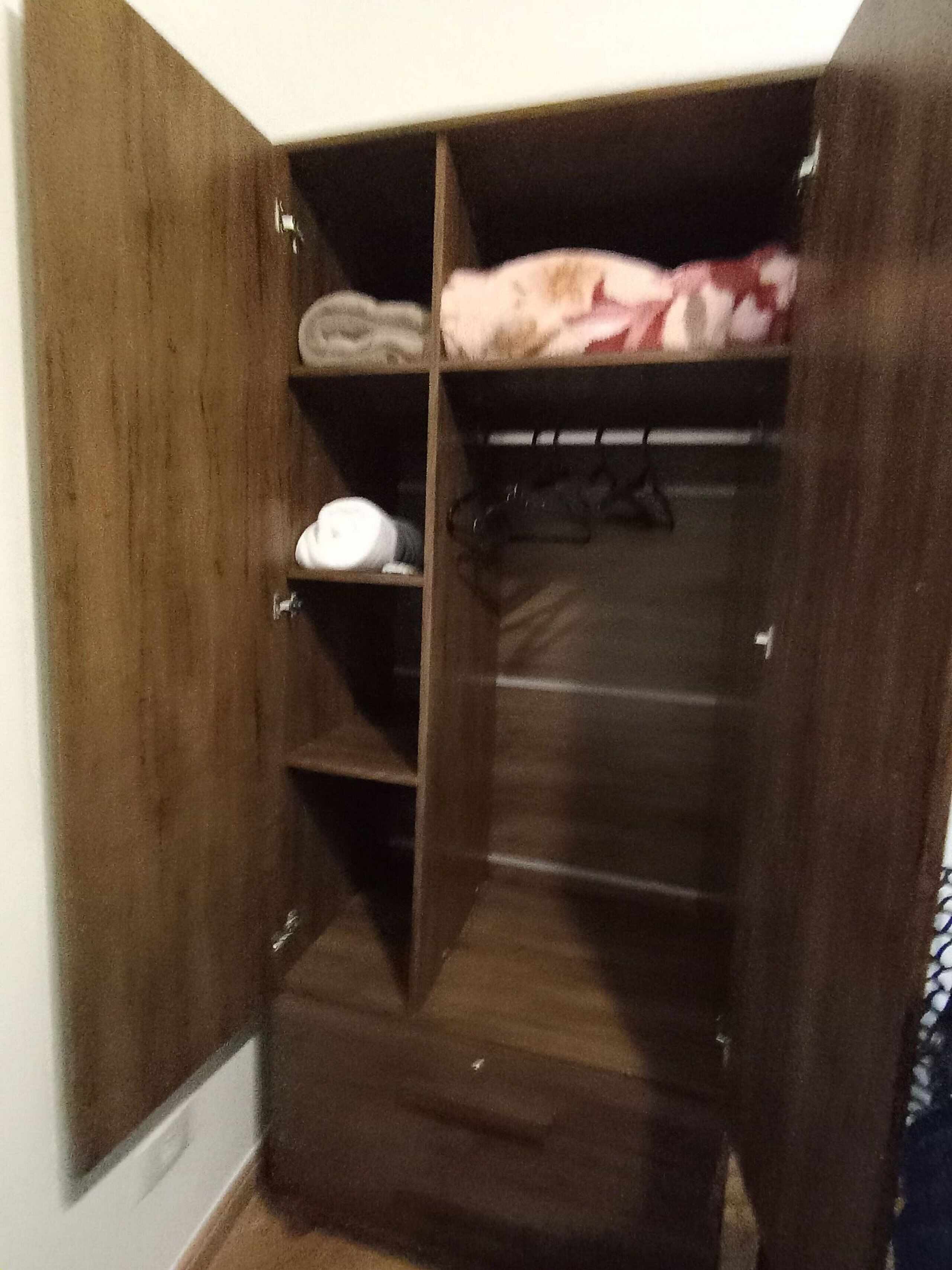 A wooden wardrobe with multiple shelves and hanging space.