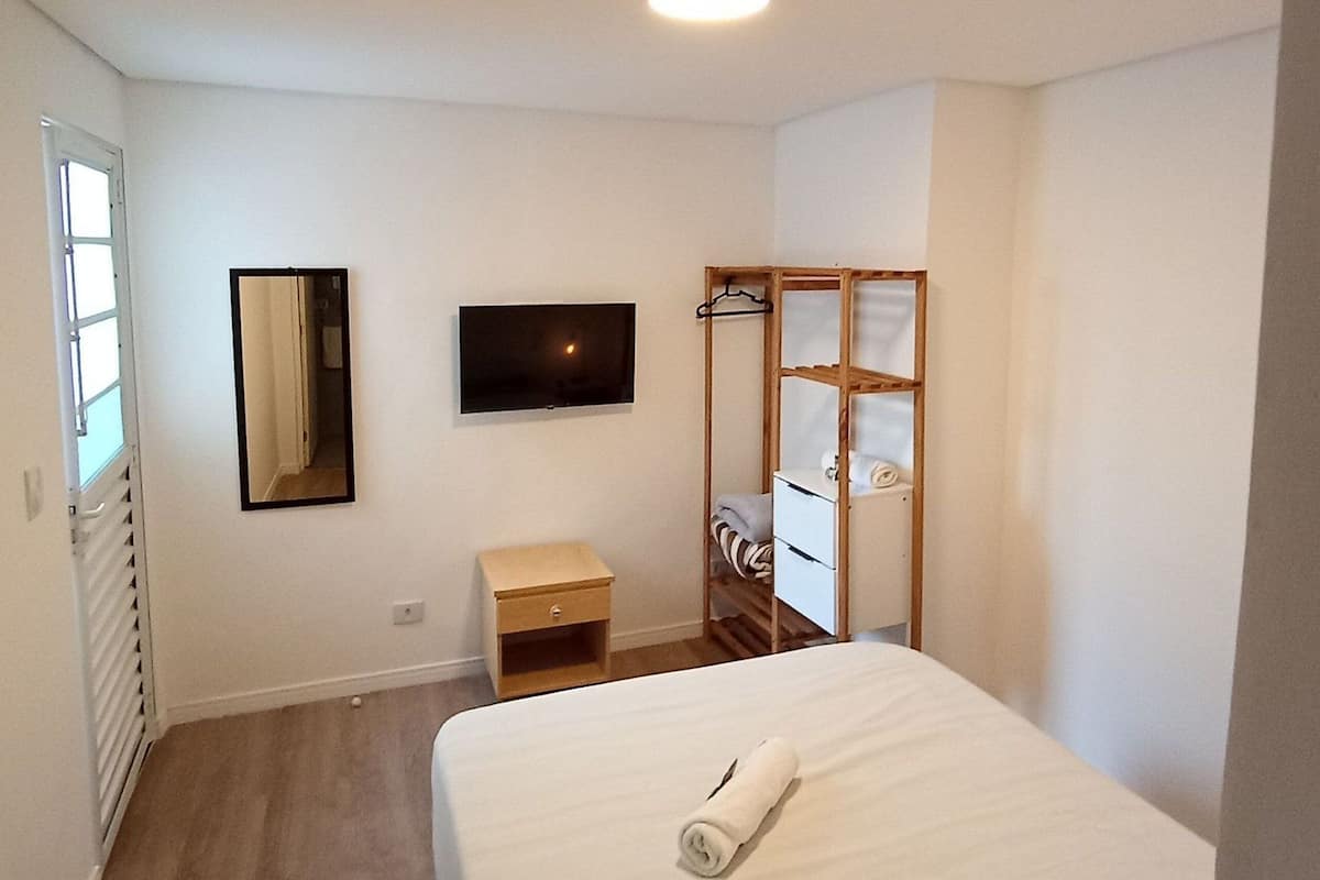 Ein Schlafzimmer mit Bett, Fernseher, Kleiderschrank und einem kleinen Nachttisch.