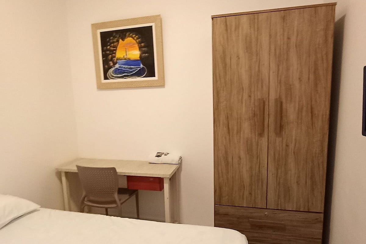 Ein Hotelzimmer mit Bett, Schreibtisch, Stuhl und Kleiderschrank.