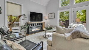 Una sala de estar moderna con chimenea, muebles de cuero y ventanas amplias.