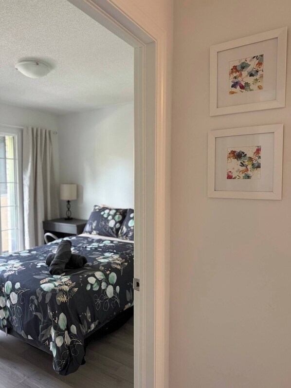 Un dormitorio con cama, un escritorio, una lámpara y dos cuadros con motivos florales en la pared.