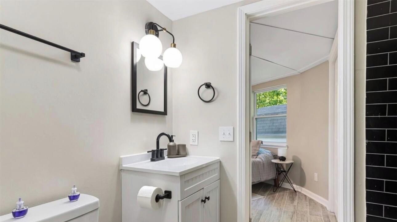 Une salle de bain avec un meuble-lavabo blanc, un miroir, un porte-serviette et des toilettes.