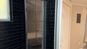 A room with a black brick wall, a sliding glass door leading to a bedroom, and a wooden floor.