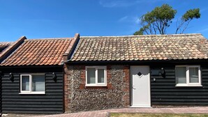 Een gebouw met twee verdiepingen, een pannendak, een bakstenen muur en een geplaveid pad.