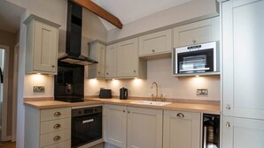 Een moderne keuken met een inbouwoven, een magnetron en een roestvrijstalen afzuigkap.