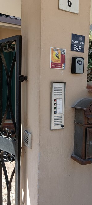 Un mur avec une porte, une boîte aux lettres et une enseigne indiquant « Moon Ash, chambres d’hôtes ».