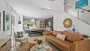 Ein modernes Wohnzimmer mit einer braunen Ledersofa, einem Essbereich mit einem Holztisch und einer Treppe mit Geländer.