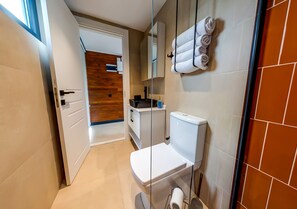 Ein modernes Badezimmer mit Toilette, Handtuchhalter und einer Wand aus Holzpaneelen.