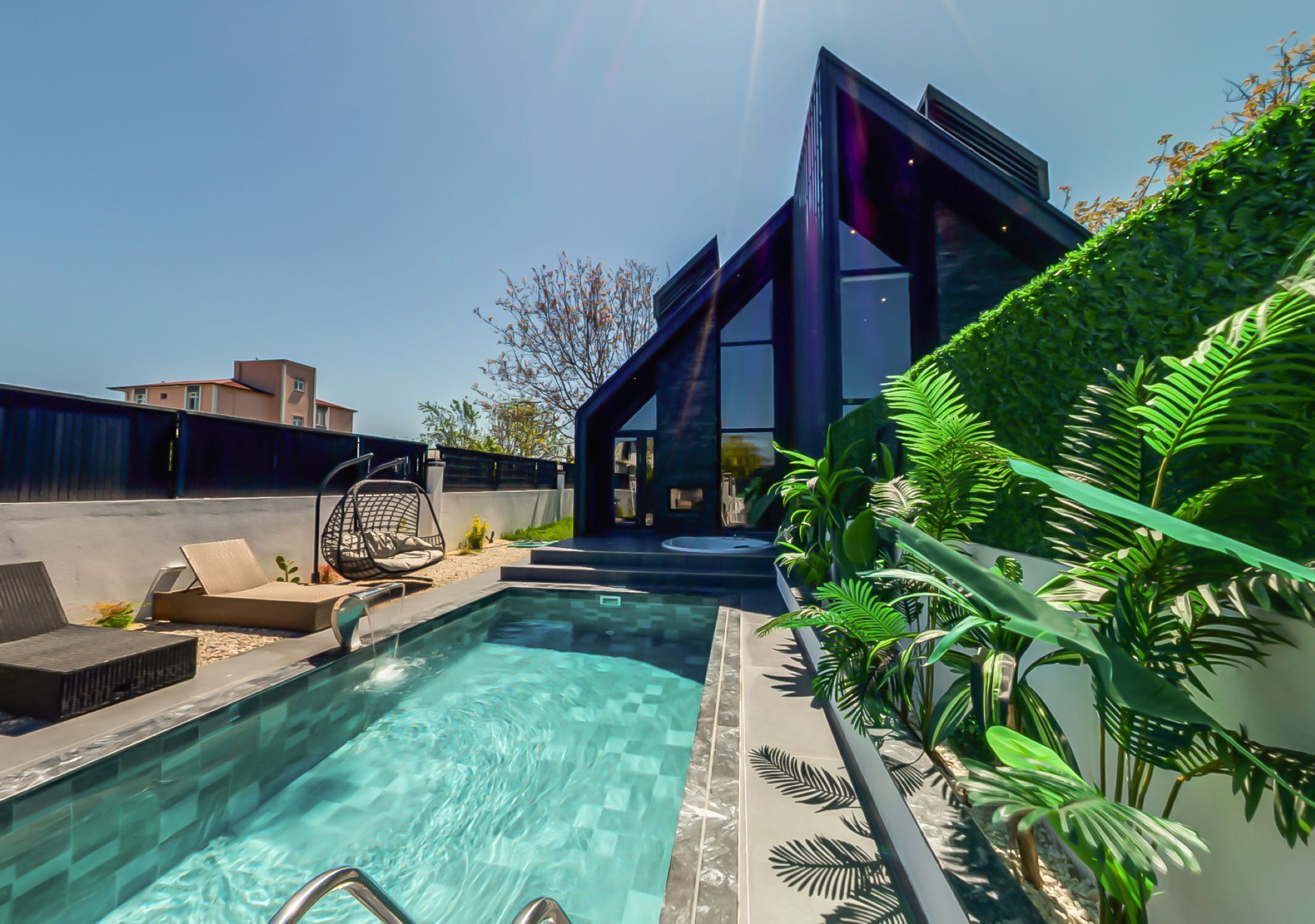 A modern outdoor pool area with a clear pool, lounge chairs, and a contemporary building in the background.